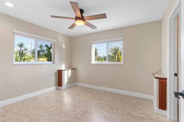 empty room with ceiling fan, light tile patterned floors, and plenty of natural light