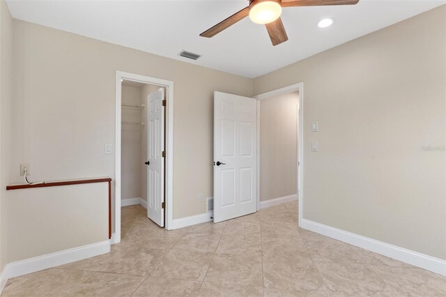 unfurnished bedroom featuring a walk in closet, a closet, light tile patterned floors, and ceiling fan