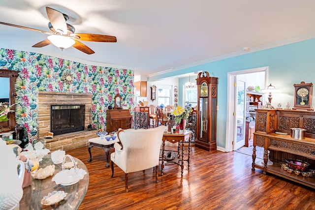 living room featuring ceiling fan with notable chandelier, crown molding, dark hardwood / wood-style flooring, and a fireplace