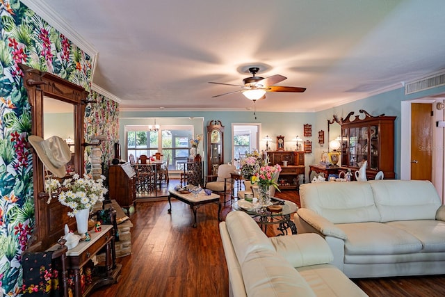 living room with dark wood-type flooring, ornamental molding, and ceiling fan with notable chandelier