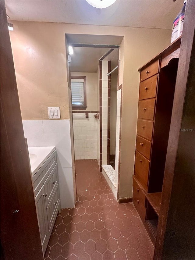 bathroom featuring vanity, tile patterned flooring, tile walls, and tiled shower