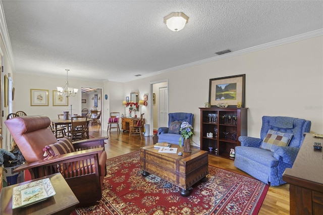 living room with a notable chandelier, ornamental molding, a textured ceiling, and hardwood / wood-style floors