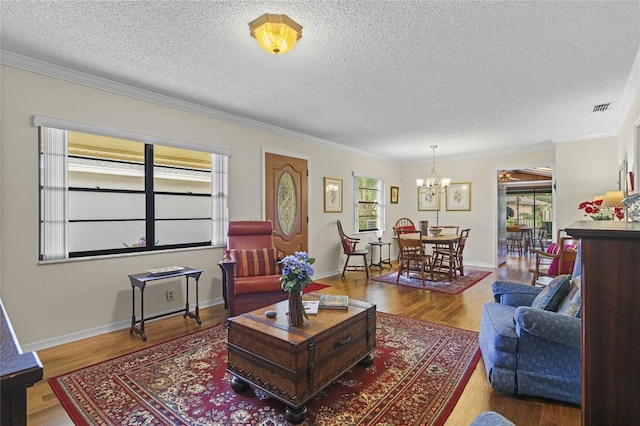 living room featuring a notable chandelier, crown molding, hardwood / wood-style flooring, and a textured ceiling