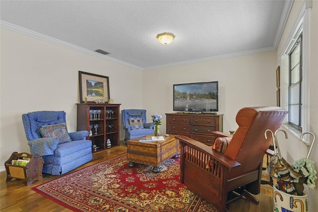 sitting room featuring a textured ceiling, ornamental molding, a wealth of natural light, and hardwood / wood-style floors