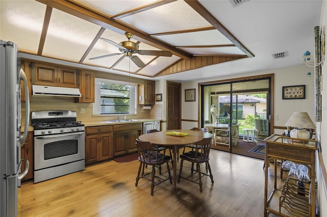 kitchen featuring ceiling fan, stainless steel appliances, light hardwood / wood-style flooring, and lofted ceiling with beams