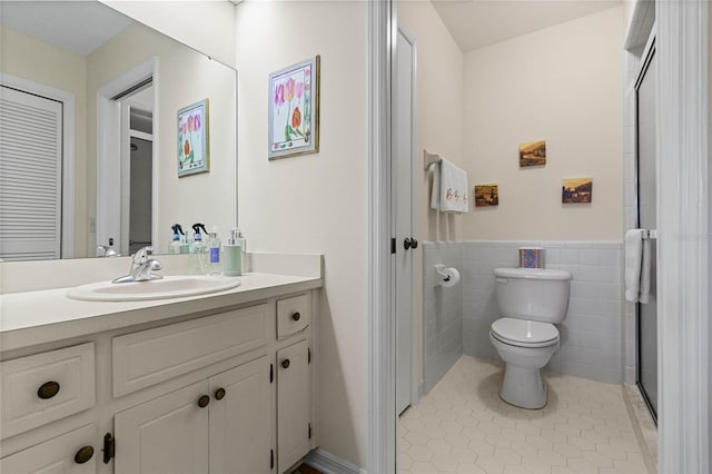 bathroom featuring toilet, vanity, tile patterned floors, and tile walls