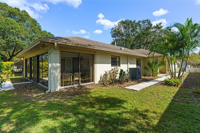 rear view of house featuring central air condition unit, a lawn, and a sunroom