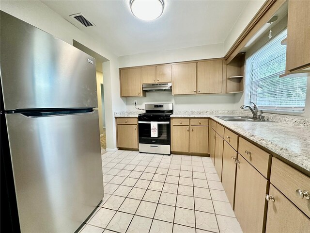 kitchen with light brown cabinets, sink, light tile patterned floors, stove, and stainless steel refrigerator