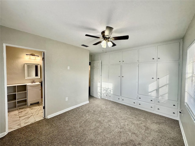 unfurnished bedroom featuring light carpet, ensuite bath, sink, a textured ceiling, and ceiling fan