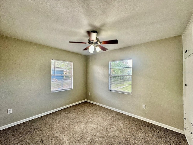 carpeted empty room with ceiling fan, a healthy amount of sunlight, and a textured ceiling