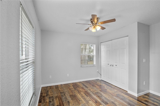 unfurnished bedroom featuring dark wood-type flooring, ceiling fan, and a closet