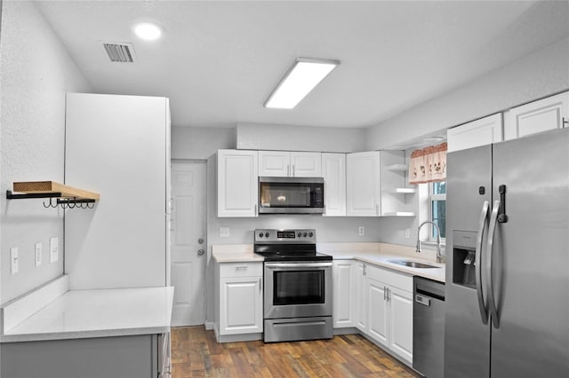 kitchen with sink, dark wood-type flooring, stainless steel appliances, and white cabinets