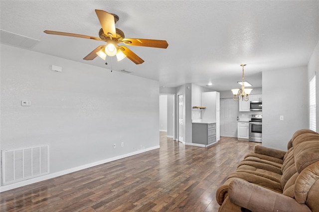 living room featuring dark wood-type flooring, ceiling fan with notable chandelier, and a textured ceiling