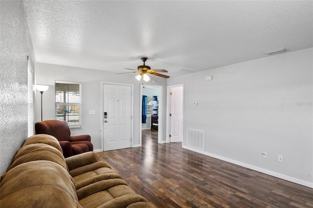 living room featuring dark hardwood / wood-style flooring, ceiling fan, and a textured ceiling