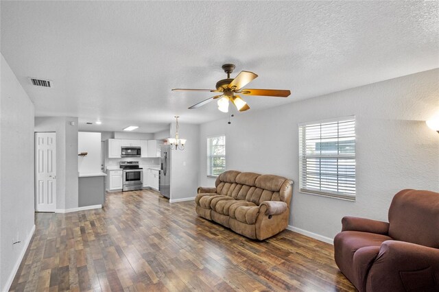 living room featuring dark wood-type flooring, ceiling fan with notable chandelier, and a textured ceiling