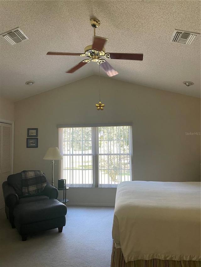 bedroom with lofted ceiling, a textured ceiling, light colored carpet, and ceiling fan