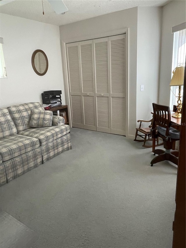 living room featuring a textured ceiling, carpet floors, and ceiling fan