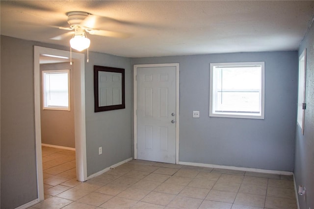 tiled foyer entrance with a textured ceiling, ceiling fan, and a wealth of natural light