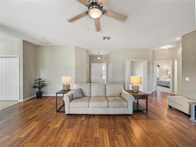 living room featuring a textured ceiling, dark wood-type flooring, and ceiling fan