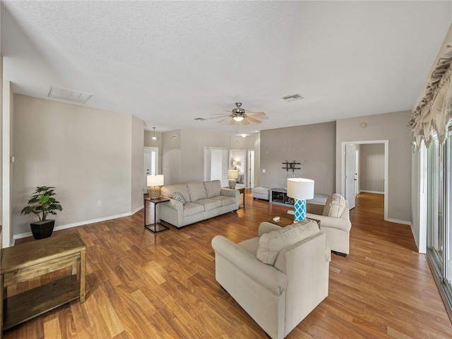 living room with a textured ceiling, hardwood / wood-style flooring, and ceiling fan