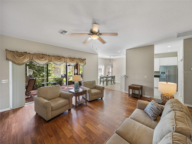 living room with a textured ceiling, hardwood / wood-style flooring, and ceiling fan