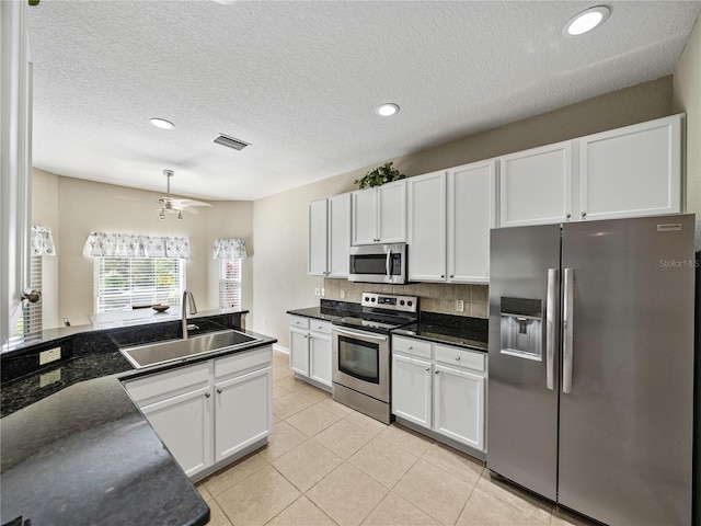 kitchen featuring stainless steel appliances, sink, tasteful backsplash, light tile patterned floors, and white cabinets