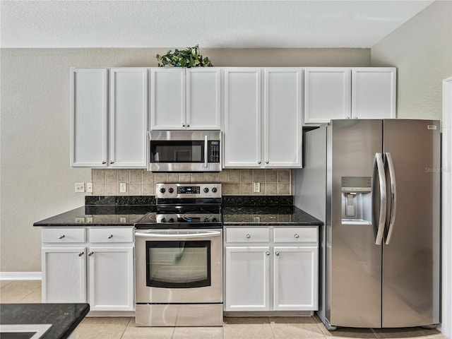 kitchen with dark stone countertops, tasteful backsplash, appliances with stainless steel finishes, and white cabinets