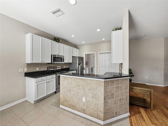 kitchen with light tile patterned flooring, stainless steel appliances, white cabinetry, sink, and kitchen peninsula