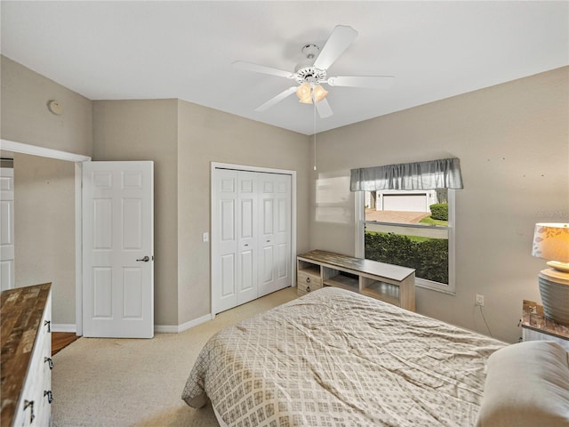 bedroom with ceiling fan, light carpet, and a closet