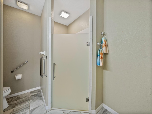 bathroom featuring toilet and a shower with shower door