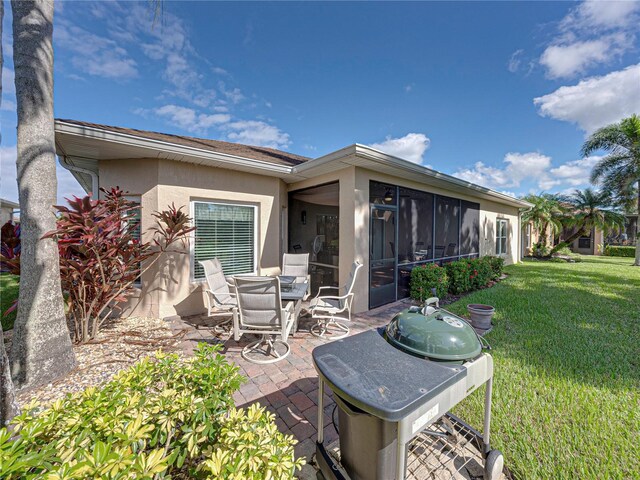 back of property with a yard, a sunroom, and a patio