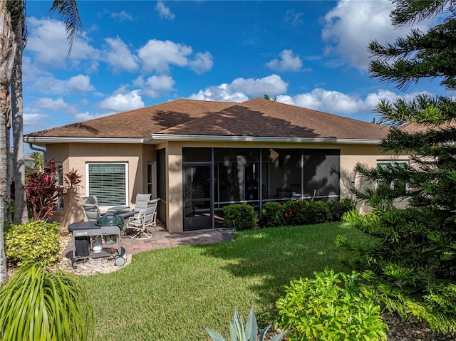 rear view of property featuring a lawn, a sunroom, and a patio