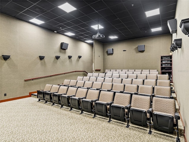 carpeted cinema room featuring a drop ceiling