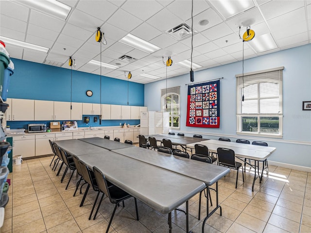 dining area featuring a drop ceiling, sink, and light tile patterned floors