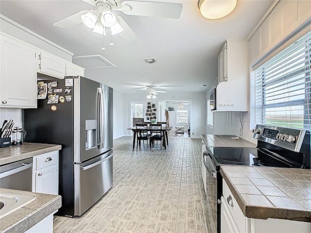 kitchen featuring appliances with stainless steel finishes, light wood-type flooring, tile countertops, backsplash, and white cabinets