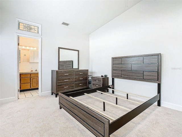 bedroom featuring light carpet and ensuite bath