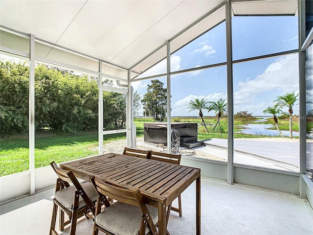 sunroom with lofted ceiling, a water view, and a healthy amount of sunlight