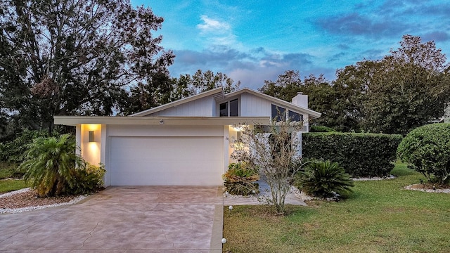 single story home with a garage and a lawn