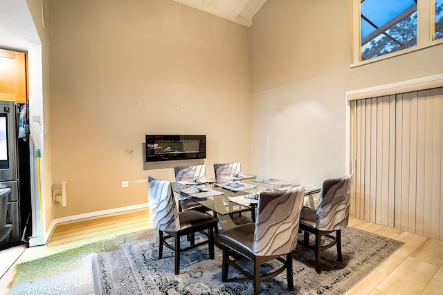 dining space featuring a high ceiling and light wood-type flooring