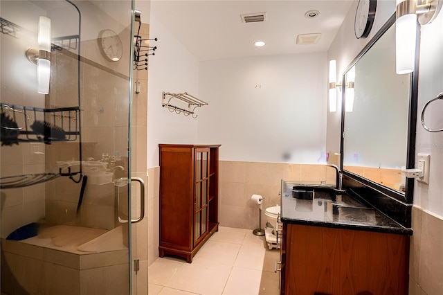 bathroom featuring tile patterned floors, toilet, tile walls, vanity, and walk in shower