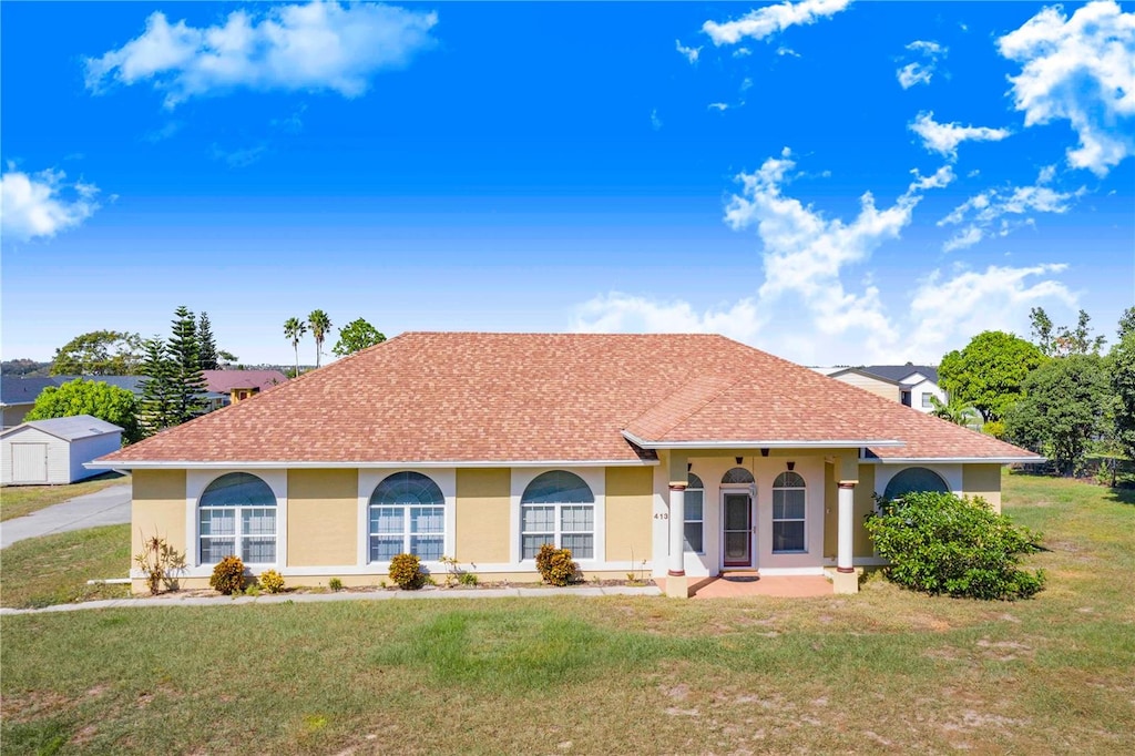 view of front of home with a storage shed and a front yard