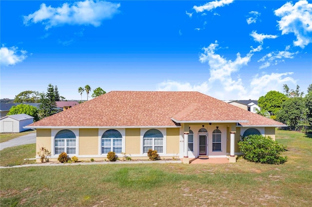 view of front of home with a storage shed and a front yard