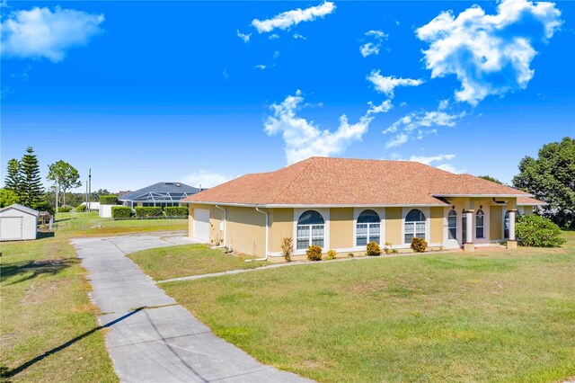 view of front of home with a shed, a garage, and a front lawn