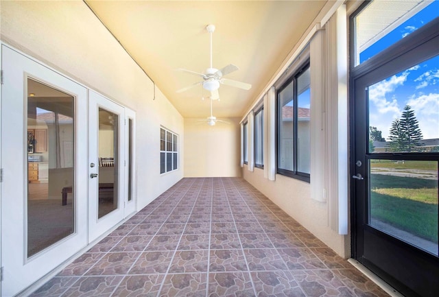 unfurnished sunroom featuring ceiling fan