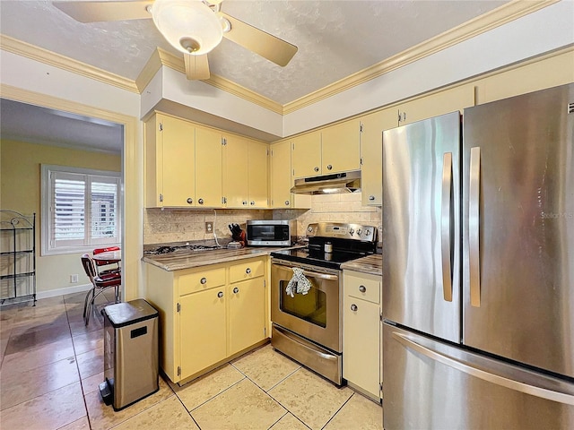 kitchen with appliances with stainless steel finishes, cream cabinetry, light tile patterned floors, and tasteful backsplash