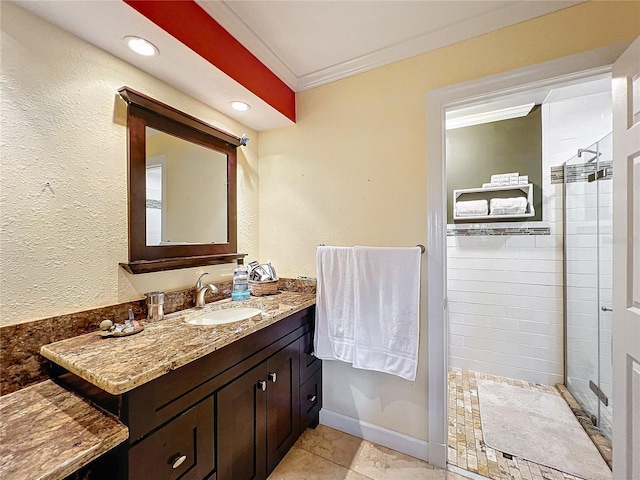 bathroom featuring vanity, crown molding, a tile shower, and tile patterned floors