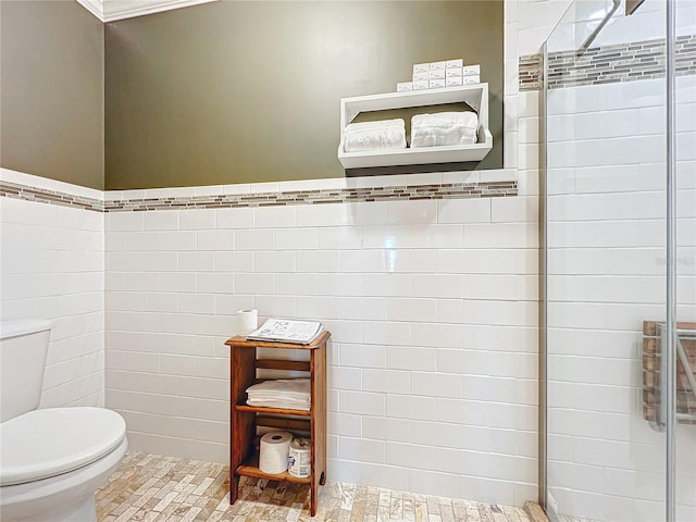 bathroom featuring toilet, an enclosed shower, and tile walls