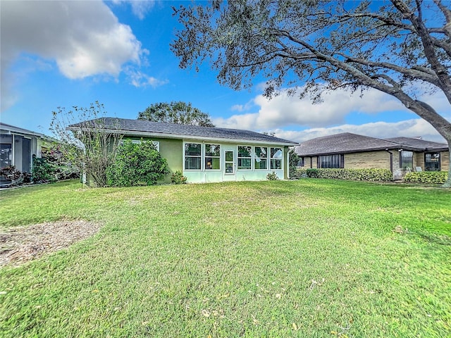 back of property featuring a sunroom and a lawn