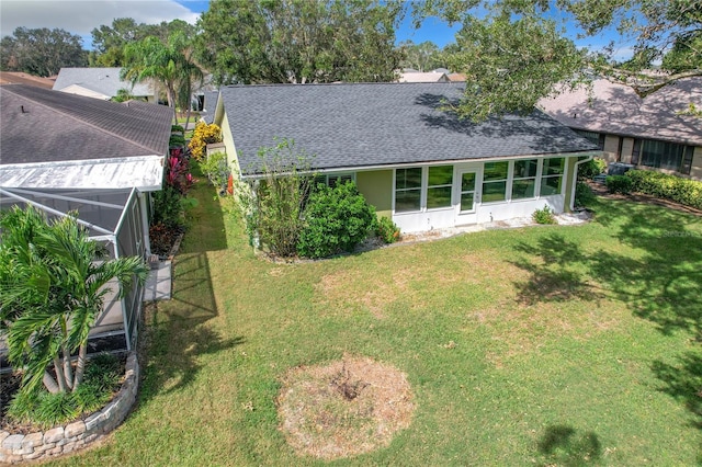 back of house featuring glass enclosure and a lawn