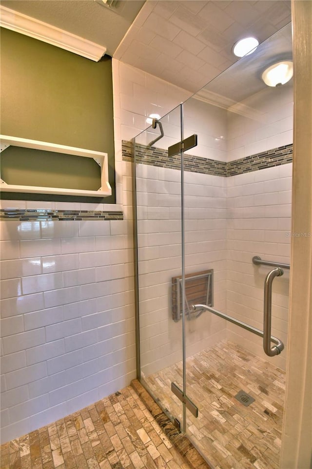 bathroom with ornamental molding and an enclosed shower